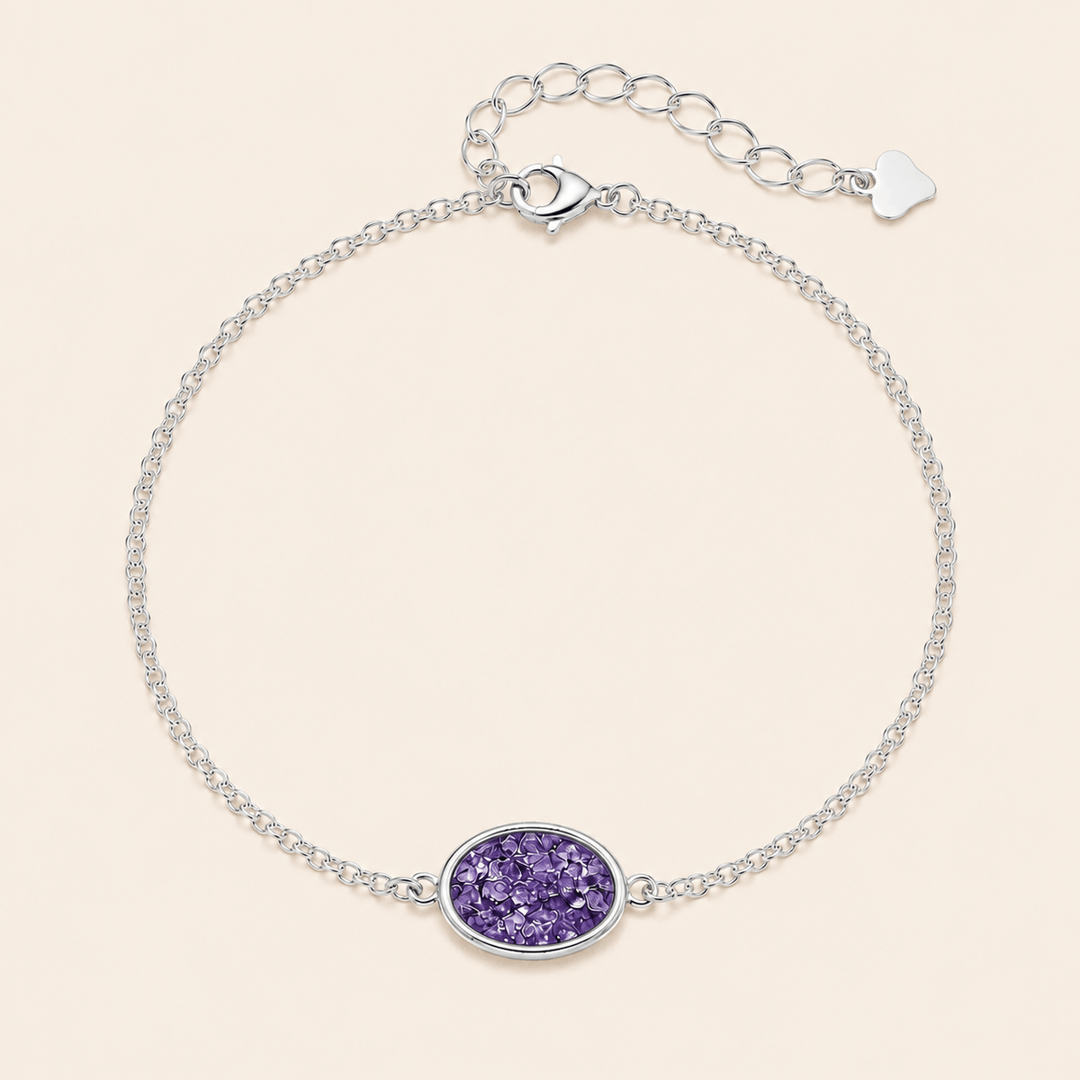 A silver chain bracelet with an oval purple glitter center, displayed on a light beige background.