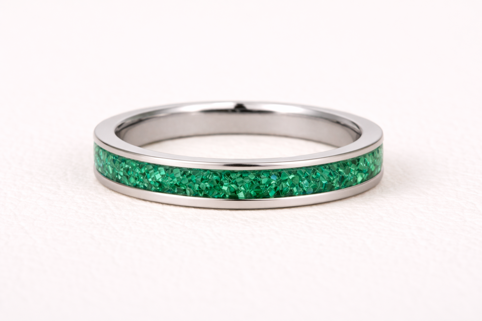 Silver ring with a green gemstone band on a white background