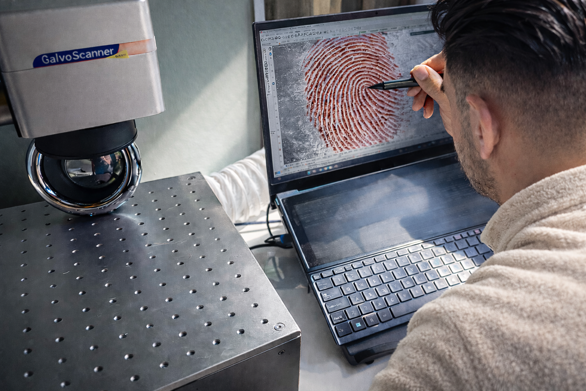 Person analyzing a fingerprint on a computer screen with a Galvo Scanner in the background.