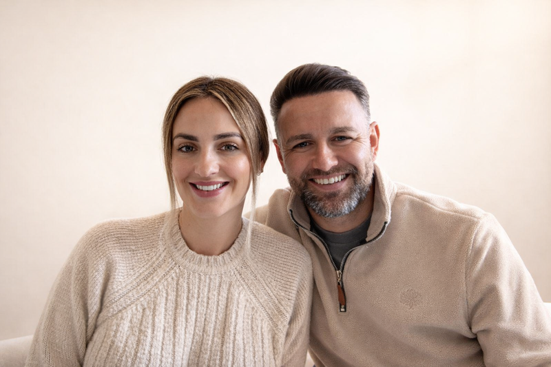 Two people posing for a photo against a plain background