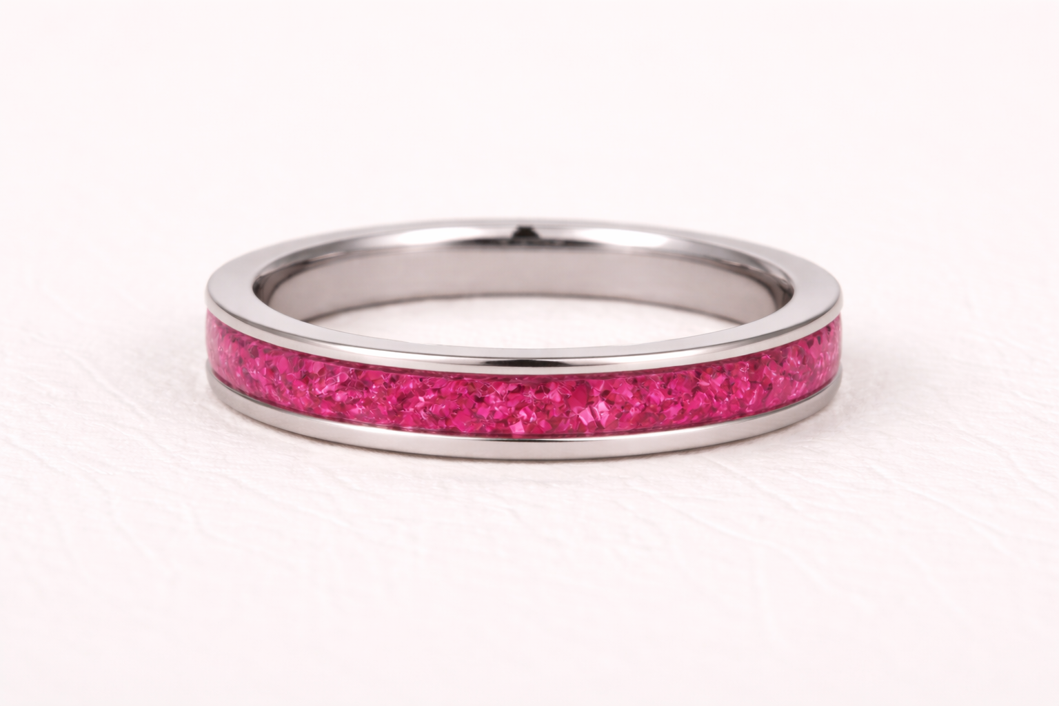 Silver ring with a pink glittery band on a white background