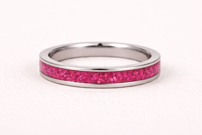 Silver ring with a pink glittery band on a white background